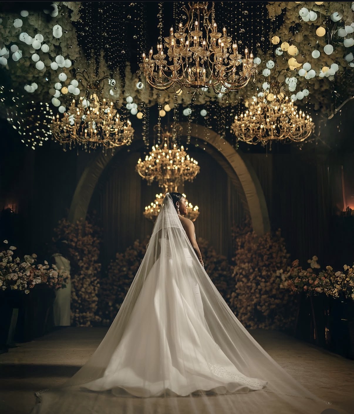 Bride under chandeliers in grand reception hall