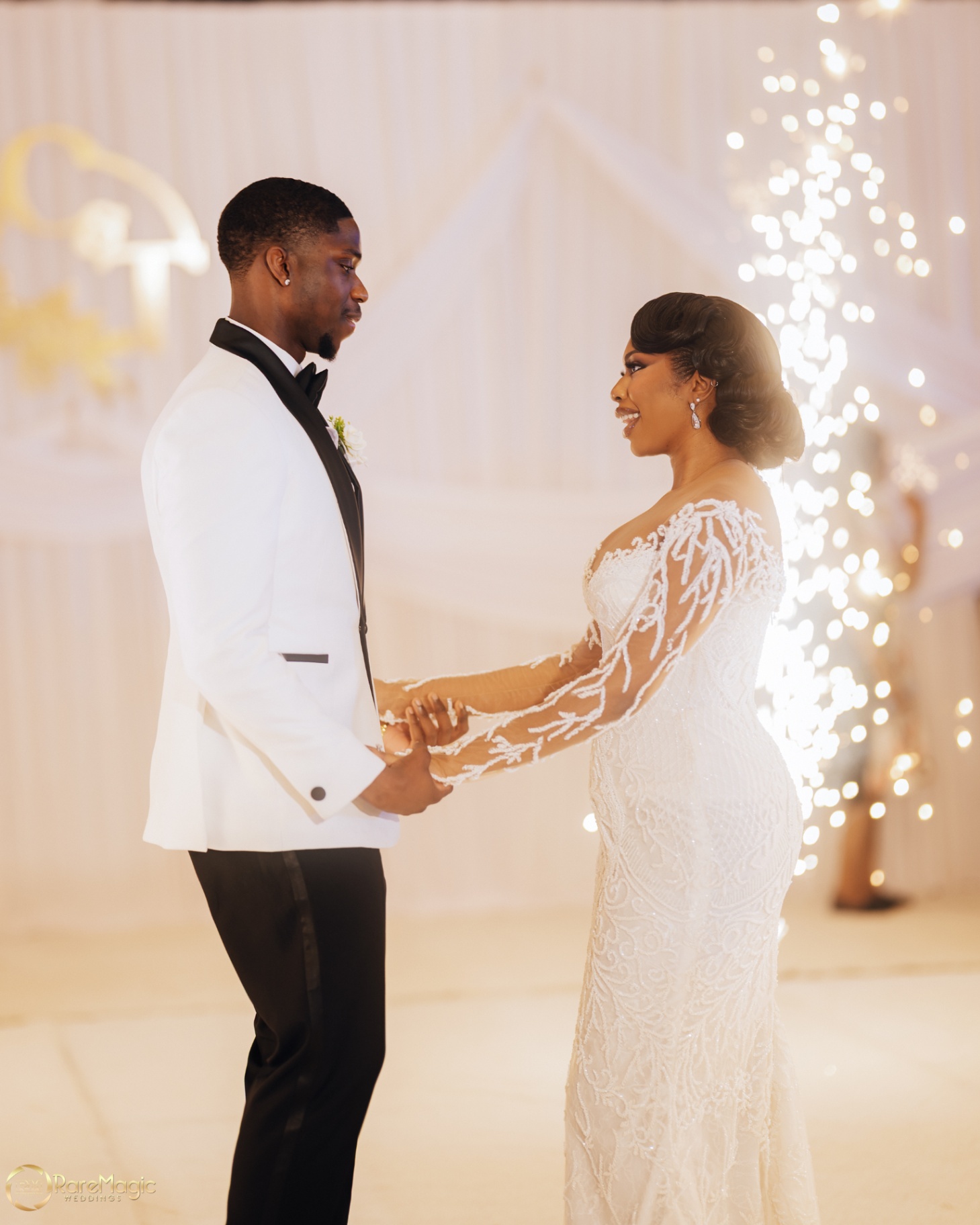 Bride and groom facing each other on the dance floor beside sparkling lights