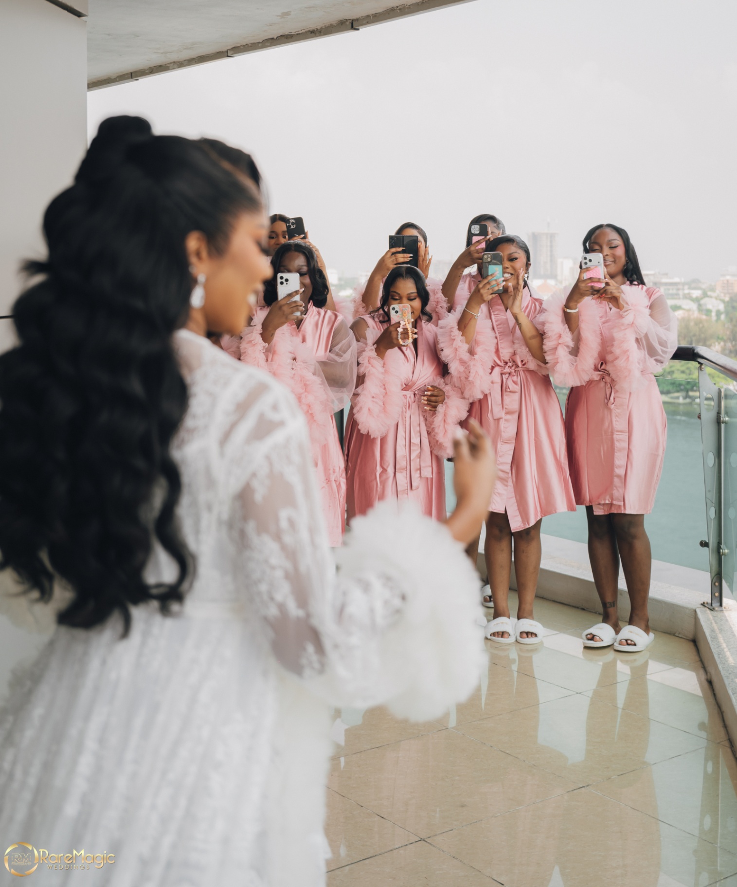 Bridesmaids in blush robes capturing the bride on their phones