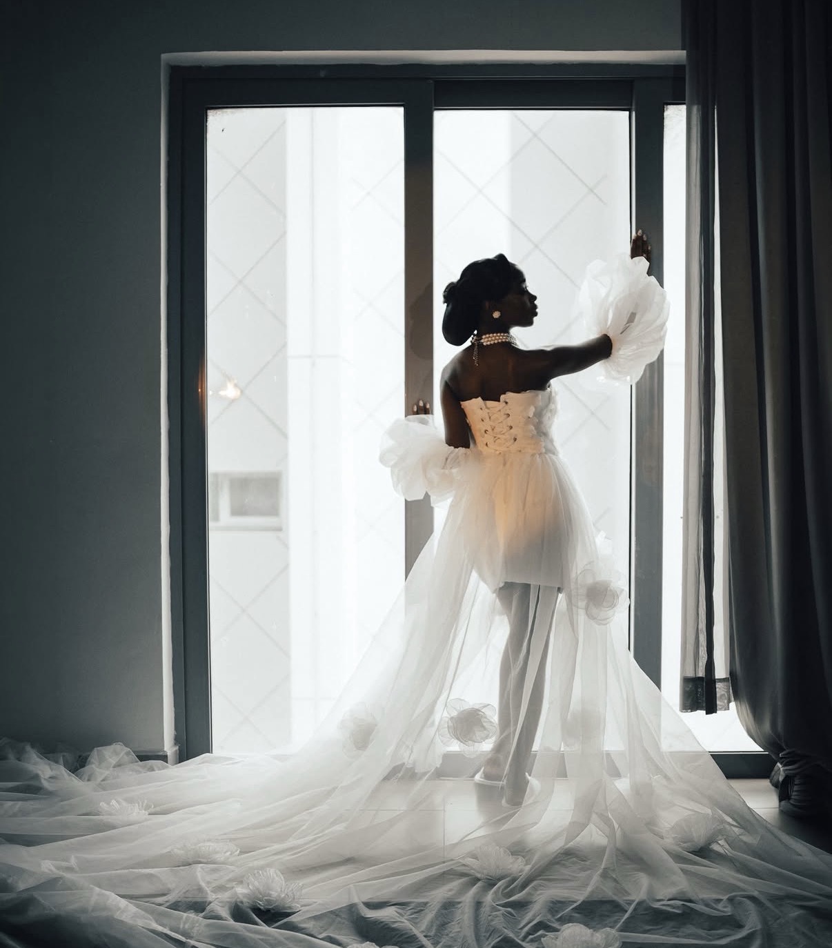 Bride silhouetted at the window in tulle gown