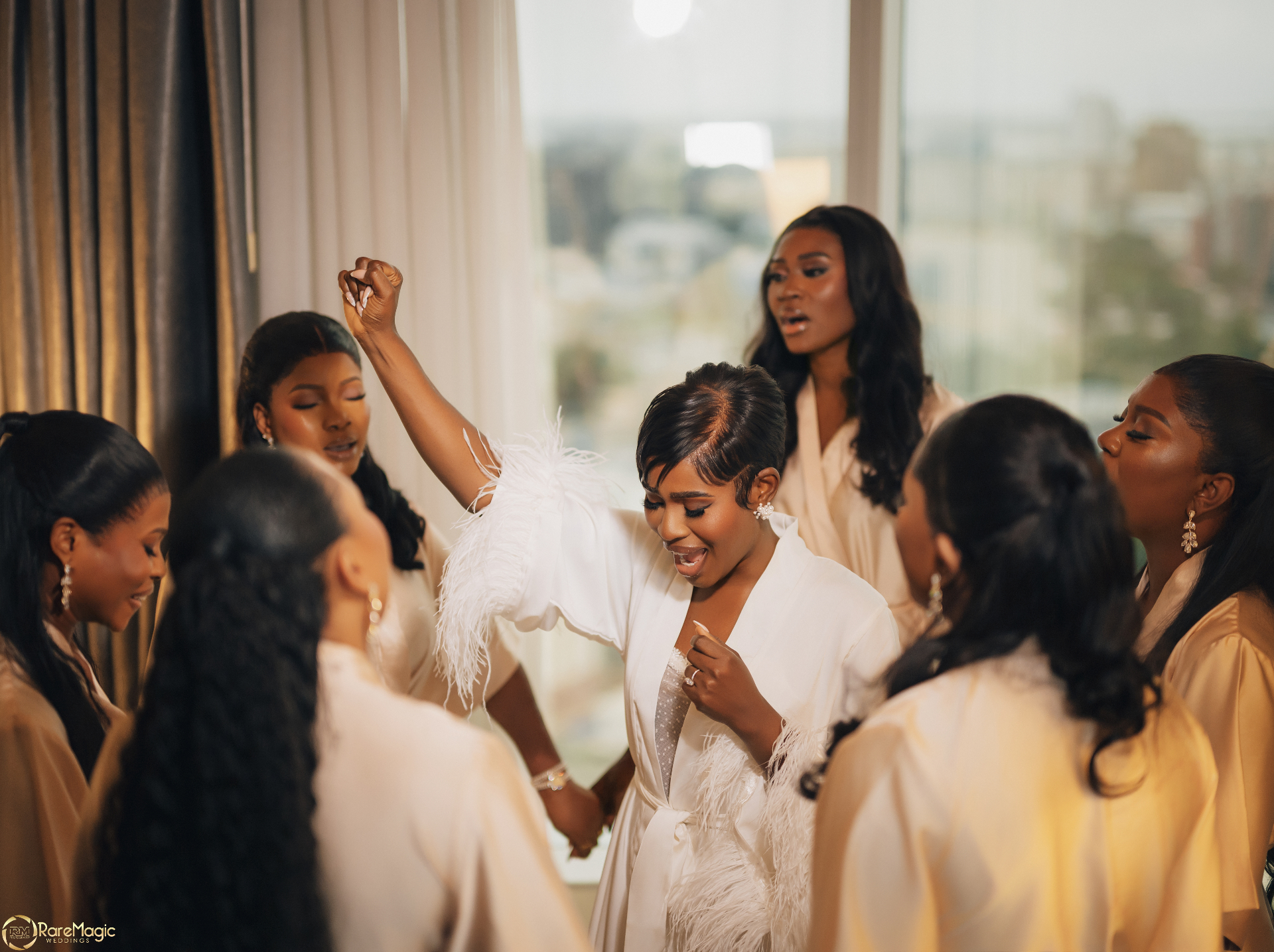 Bride surrounded by bridesmaids singing during morning preparations