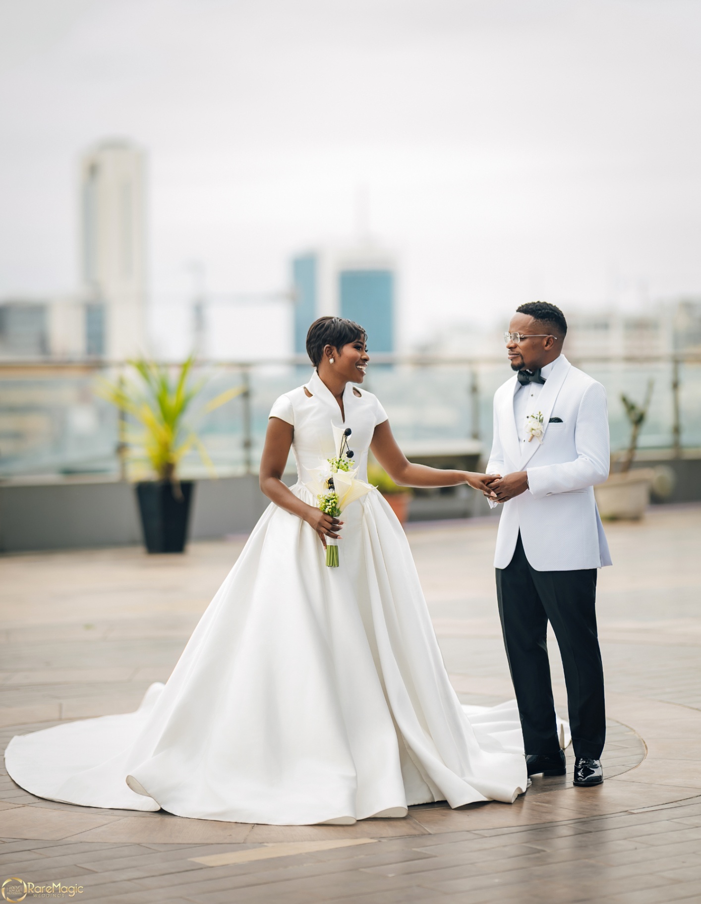 Bride and groom holding hands on the rooftop with city backdrop