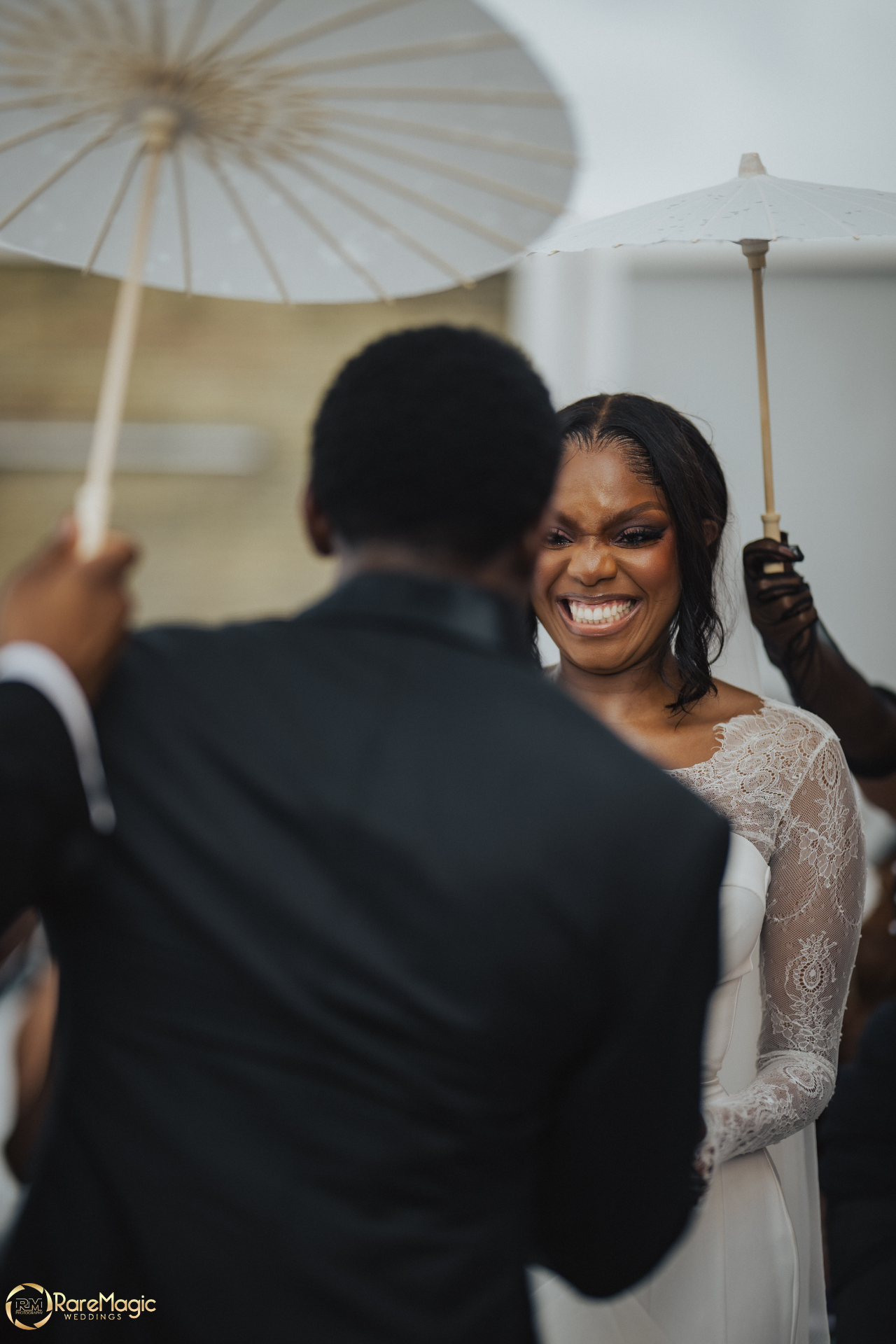 Bride smiling during the ceremony beneath white umbrellas