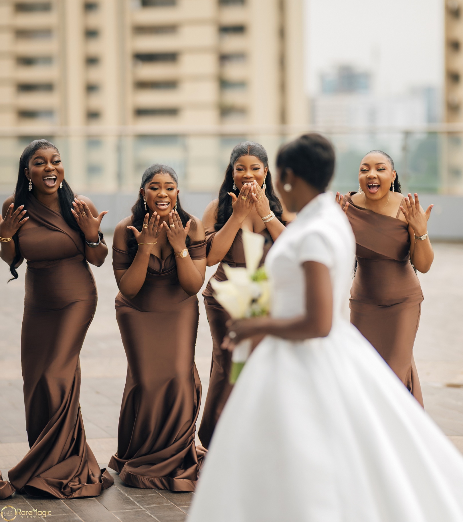 Bridesmaids in brown gowns reacting to the bride's reveal