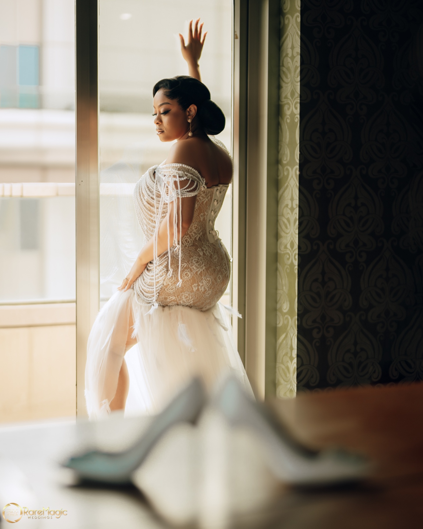 Bride by the window in a pearl corset gown with feathered tulle skirt