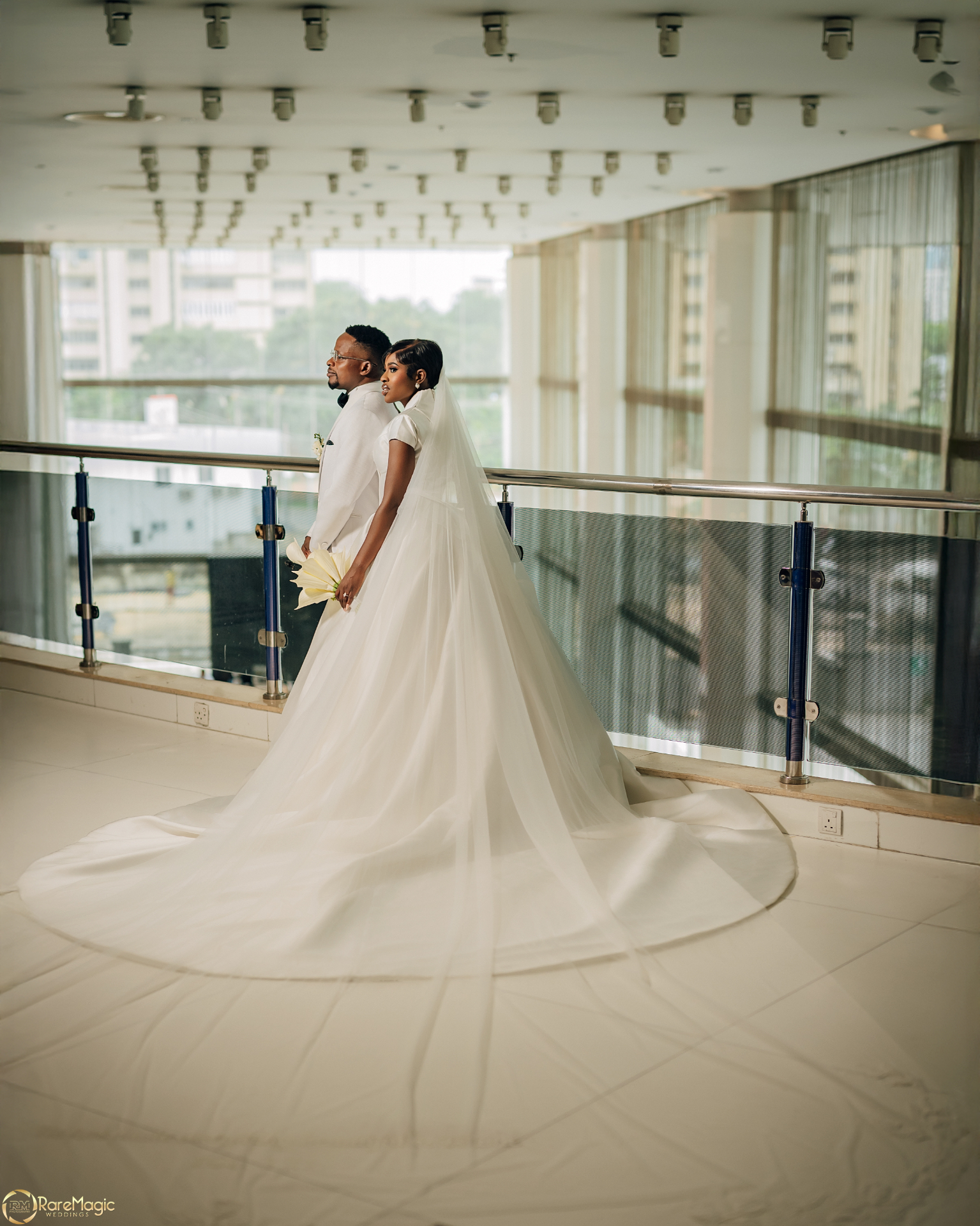 Bride and groom standing together with the bride's veil flowing across the floor