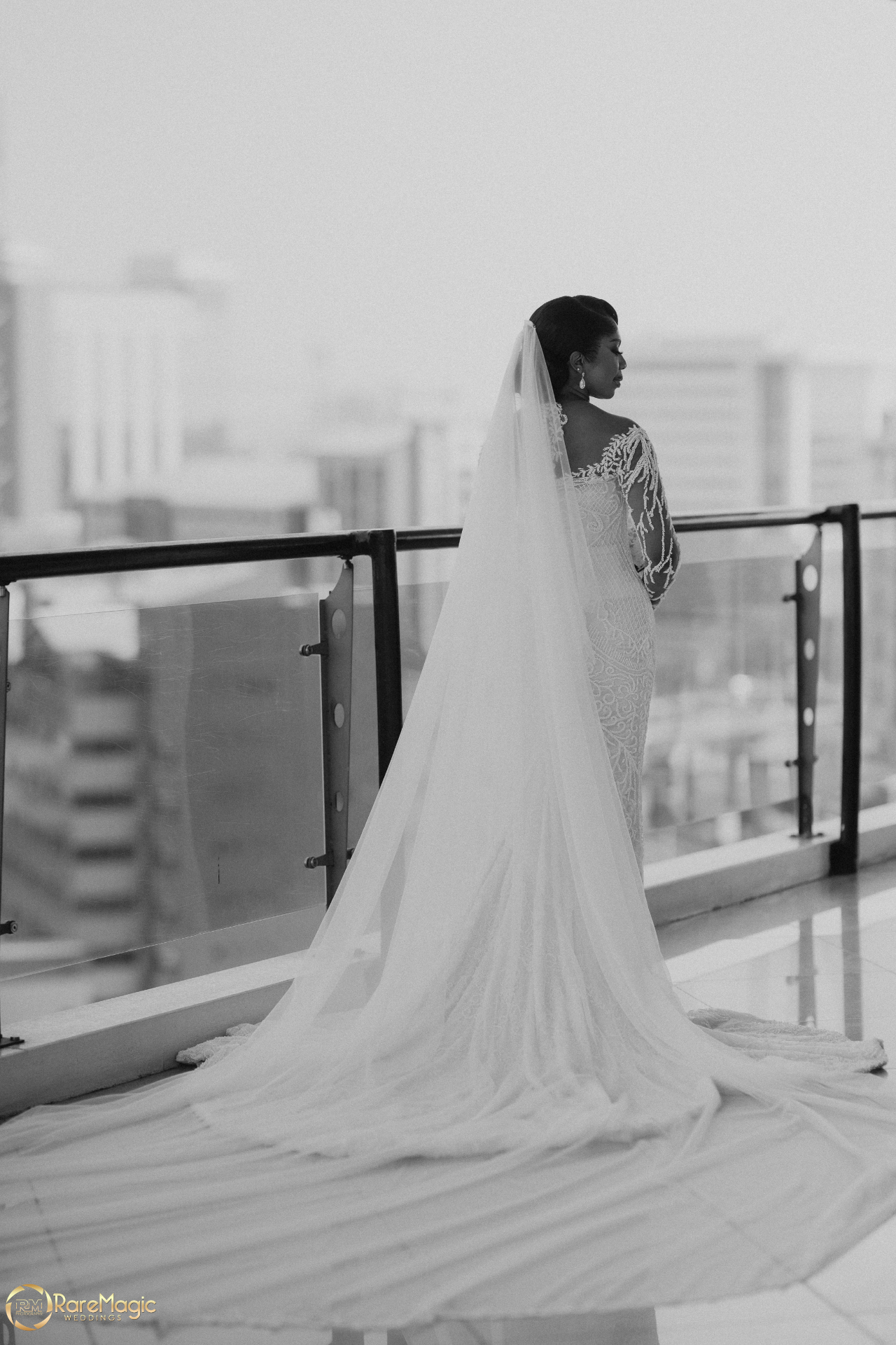Black and white bridal portrait on a city balcony with sweeping veil