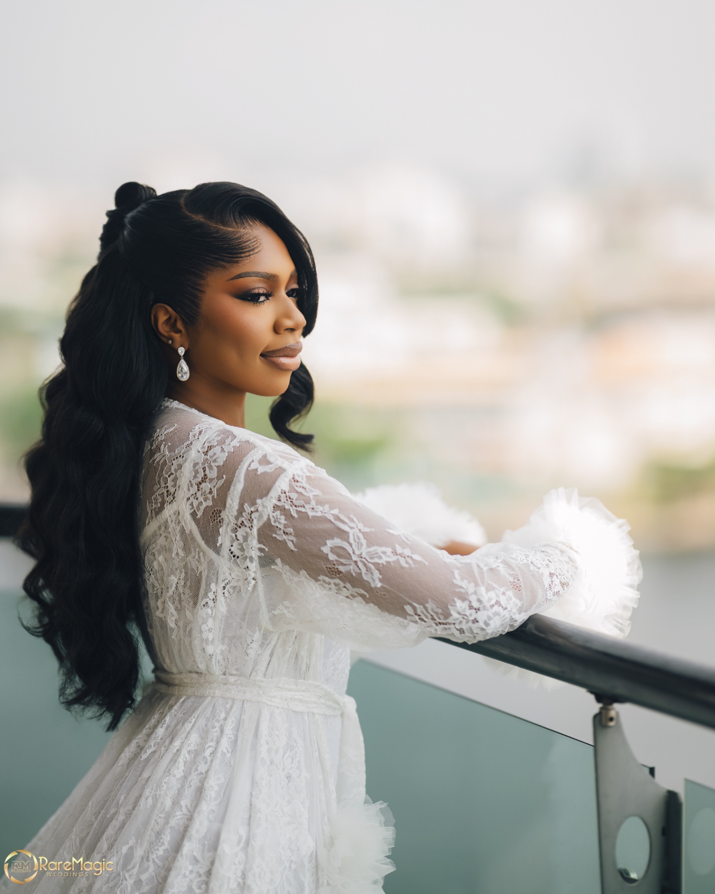 Bride leaning on the balcony in a lace robe overlooking the city