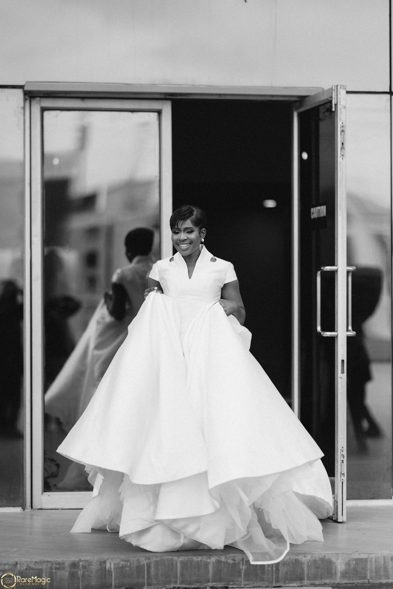 Bride smiling outside as she lifts her layered ball gown