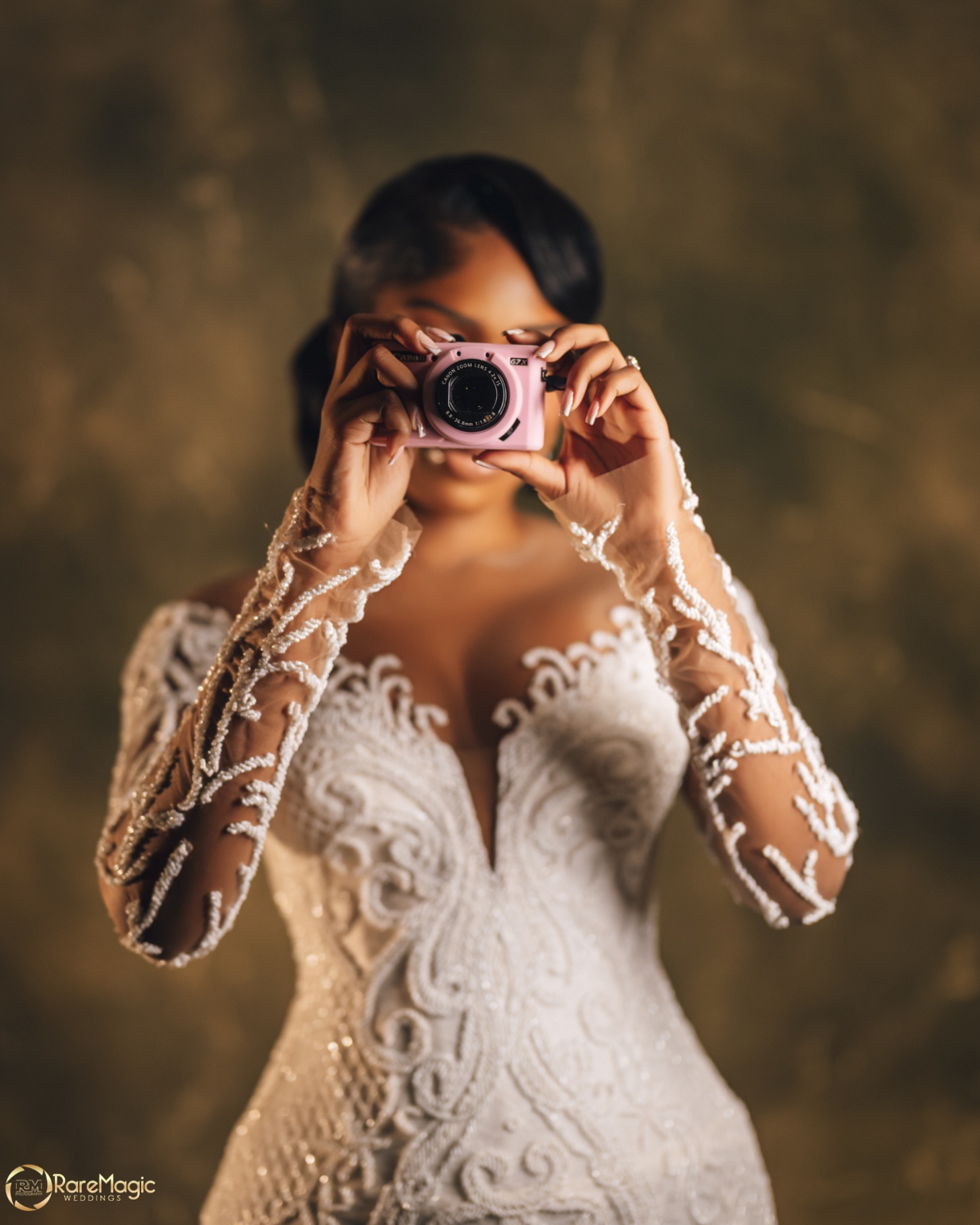 Bride playfully holding a pink compact camera to her face