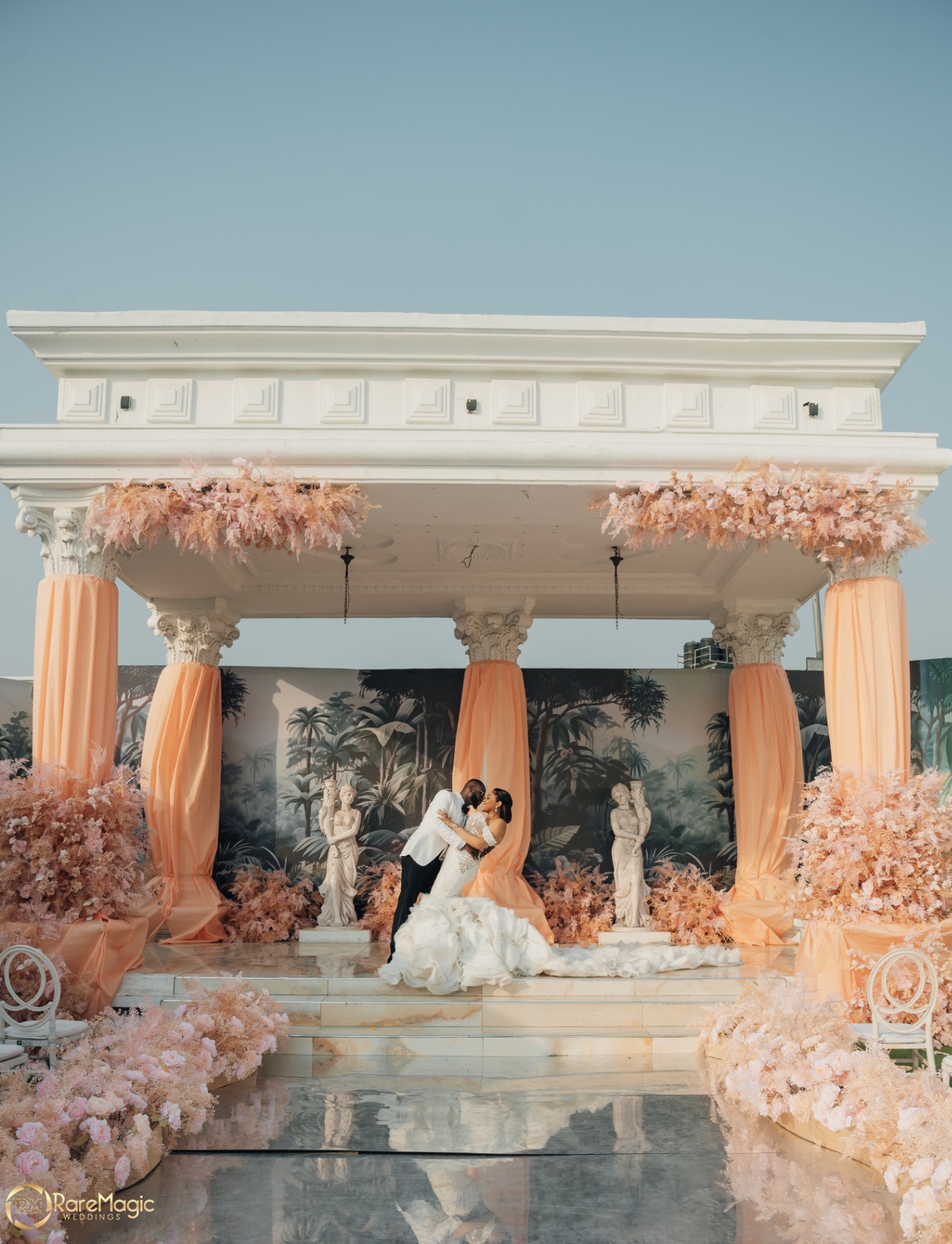 Couple kissing on a classical pavilion stage draped in peach florals