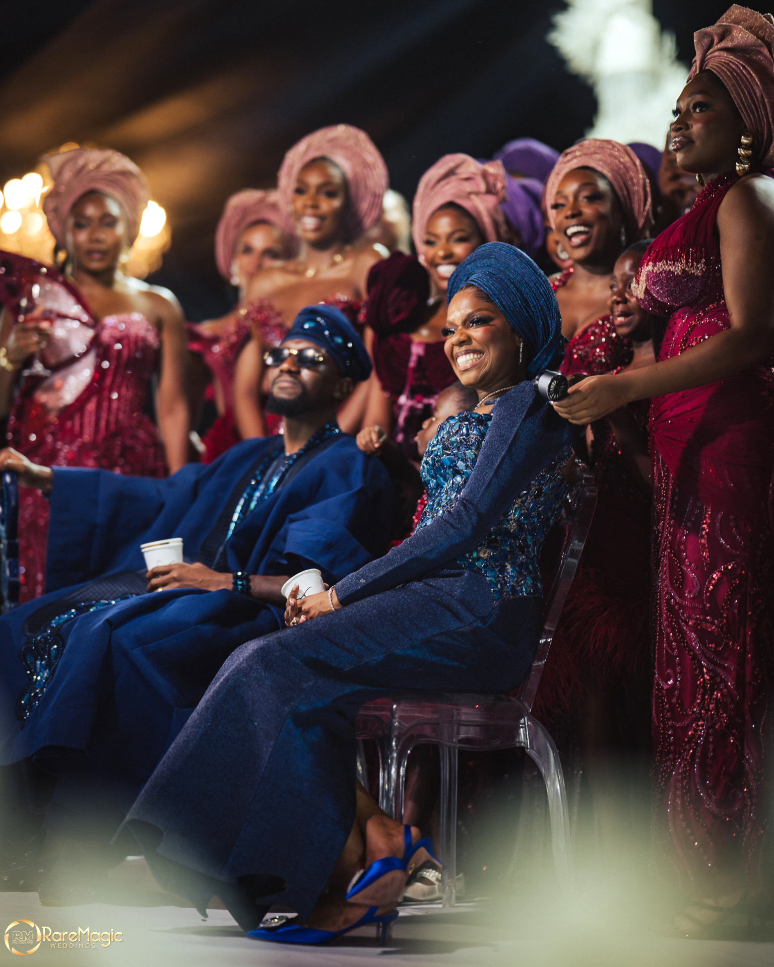 Bride and groom seated as the bridal party celebrates around them