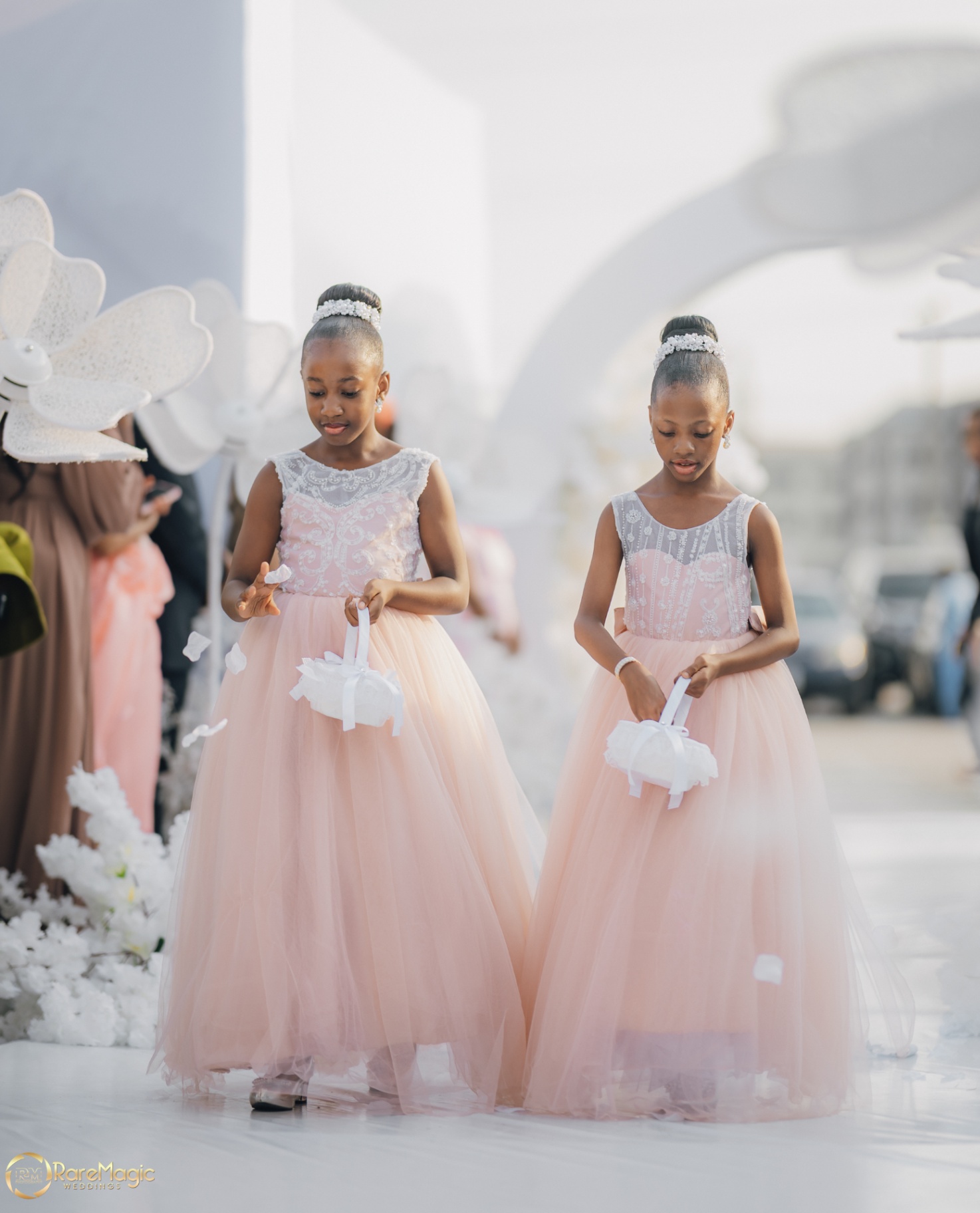 Two flower girls in blush tulle gowns walking down the aisle
