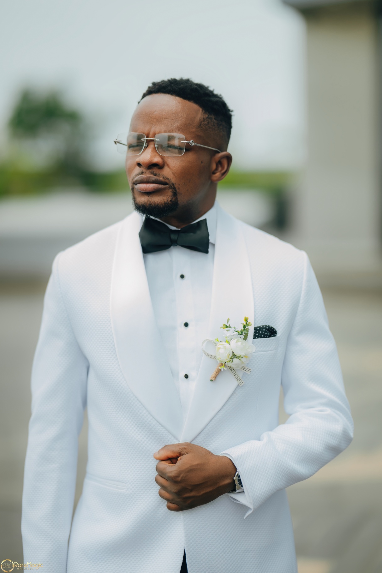 Groom portrait in a white tuxedo jacket and black bow tie