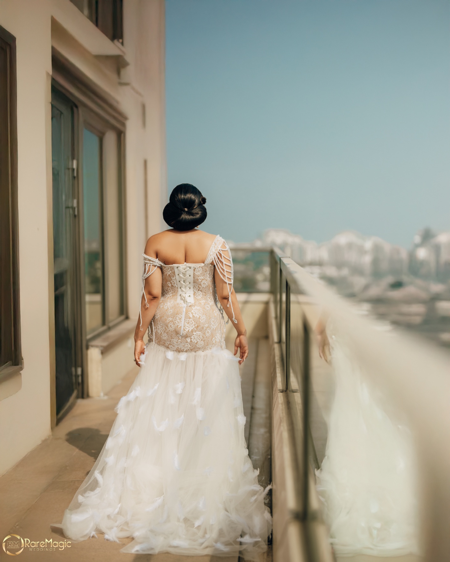 Back view of the bride on the balcony in a corseted feathered gown