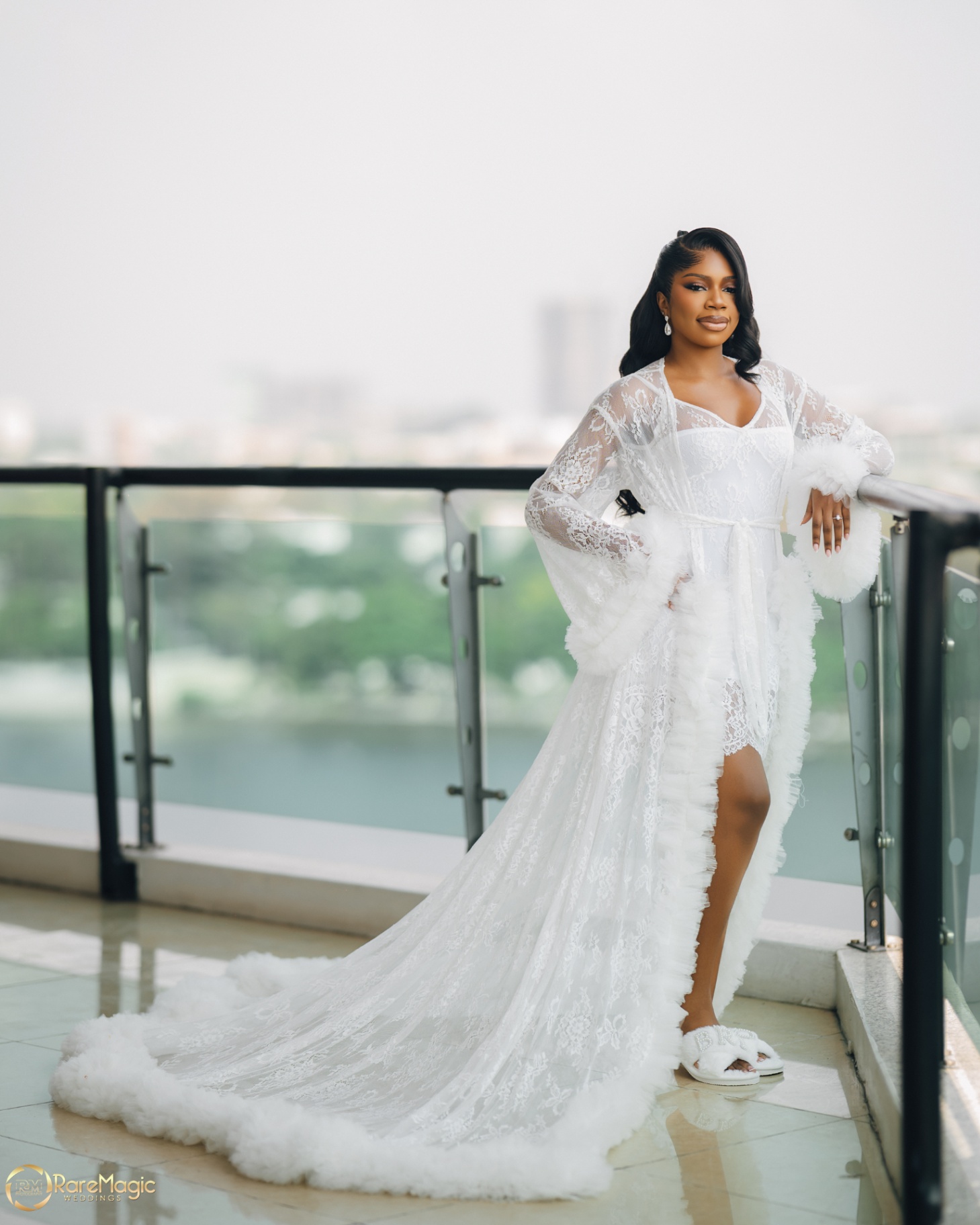 Bride posing by the balcony railing in a feather-trimmed robe