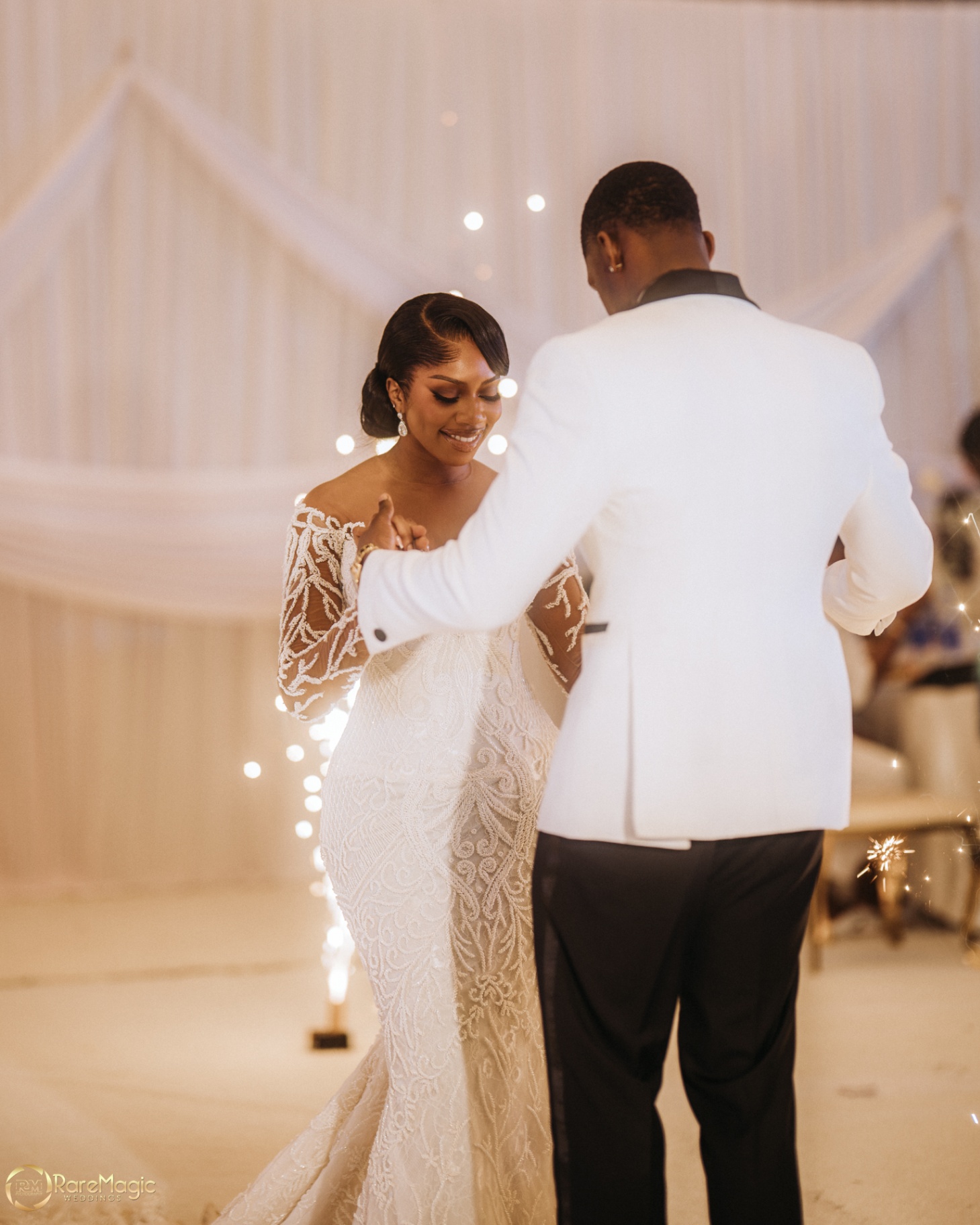 Bride smiling during the first dance with sparklers glowing behind them