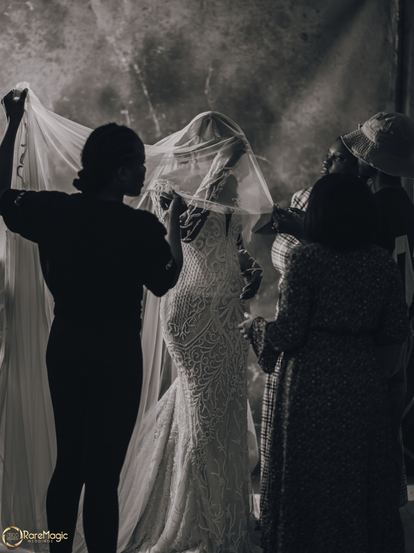 Black and white moment of family adjusting the bride's veil
