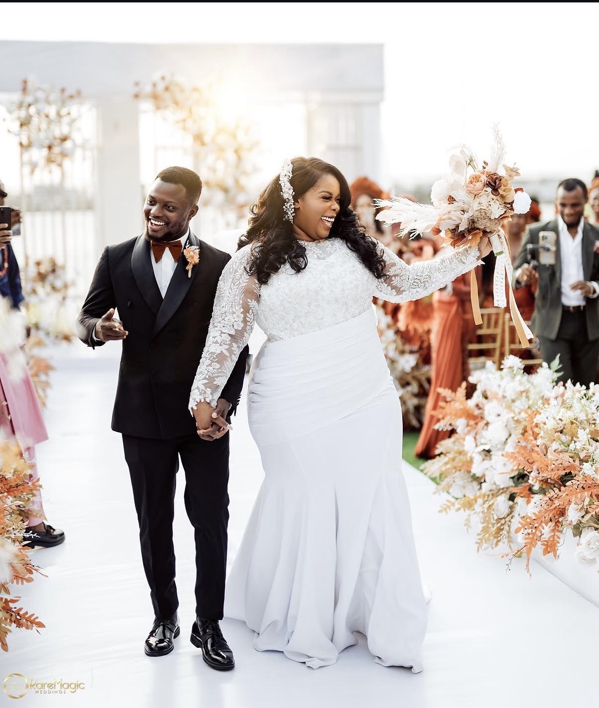 Bride and groom walking down the aisle with bouquet raised