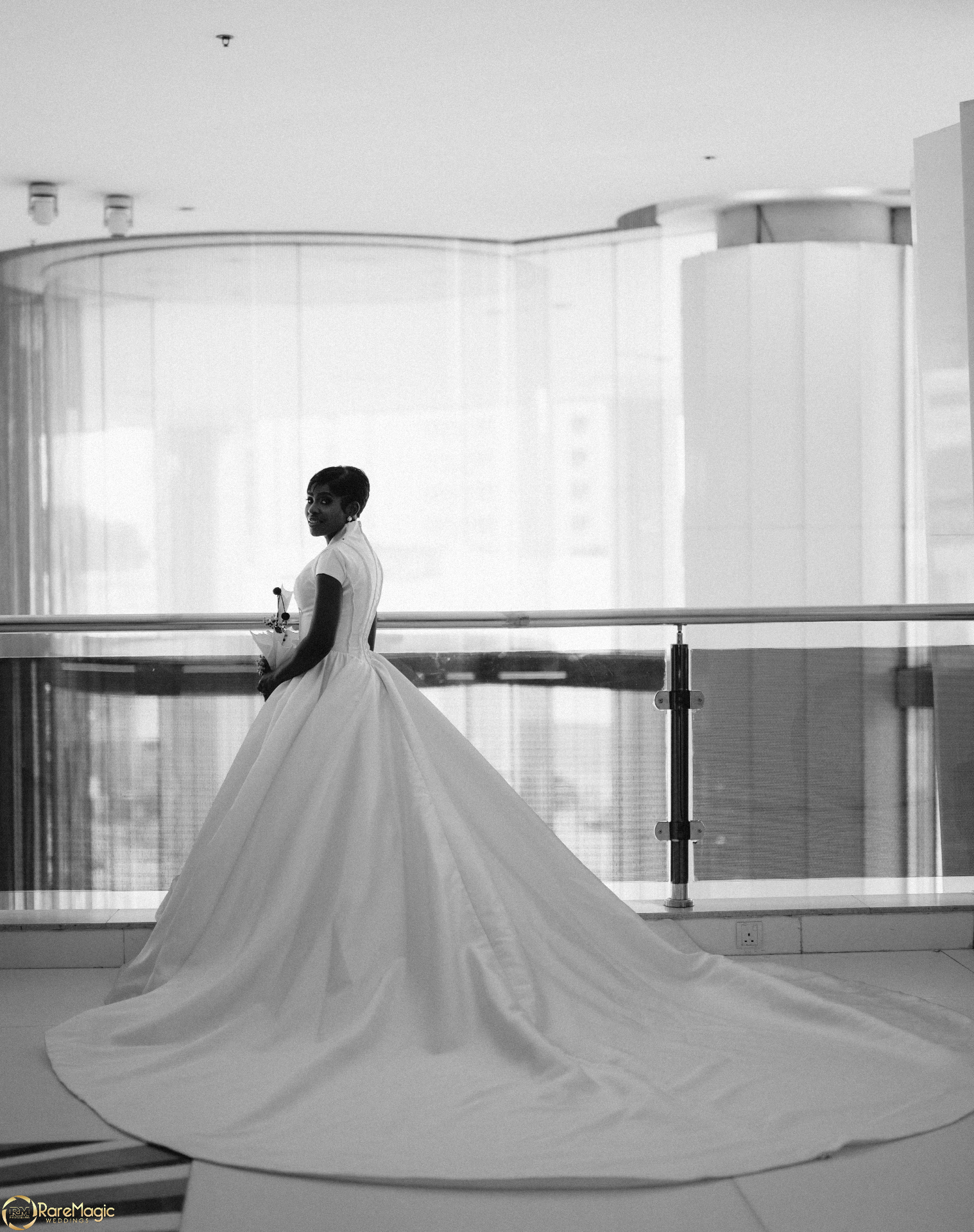 Black and white portrait of the bride with a sweeping gown train in a modern interior