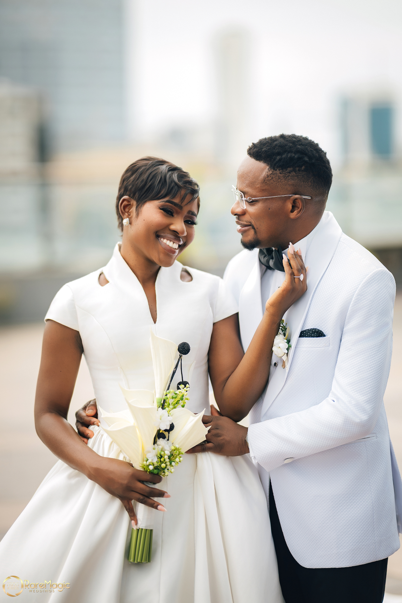 Bride and groom in white wedding attire sharing a soft portrait together