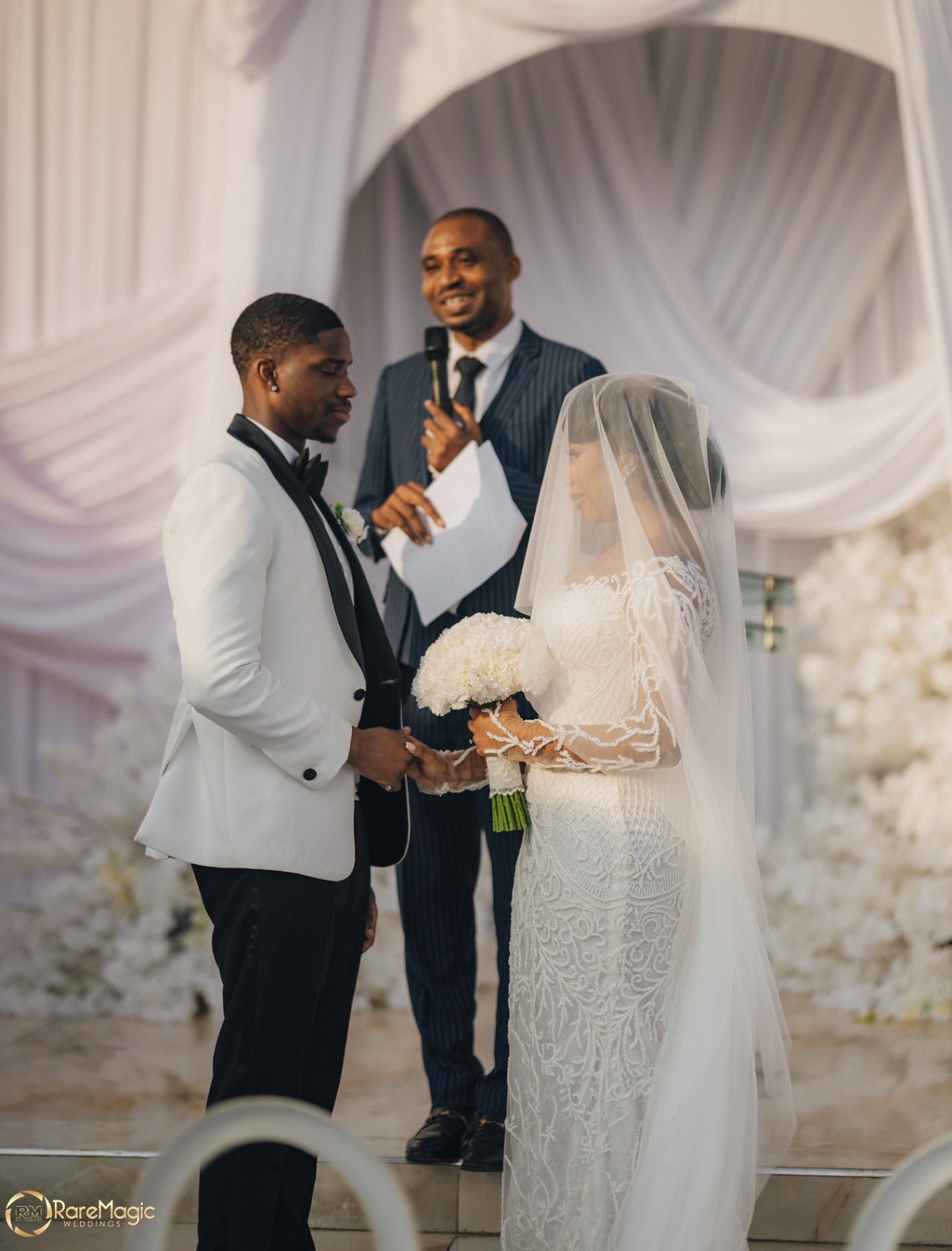 Bride and groom exchanging vows beneath soft drapery during the ceremony