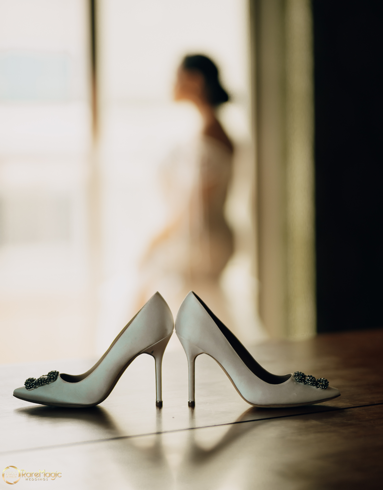 Bridal heels on the floor with the bride softly out of focus behind