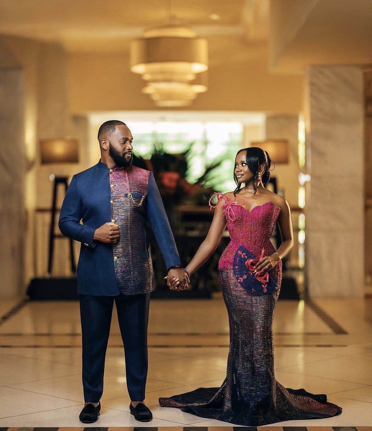 Couple in regal attire holding hands in hotel lobby